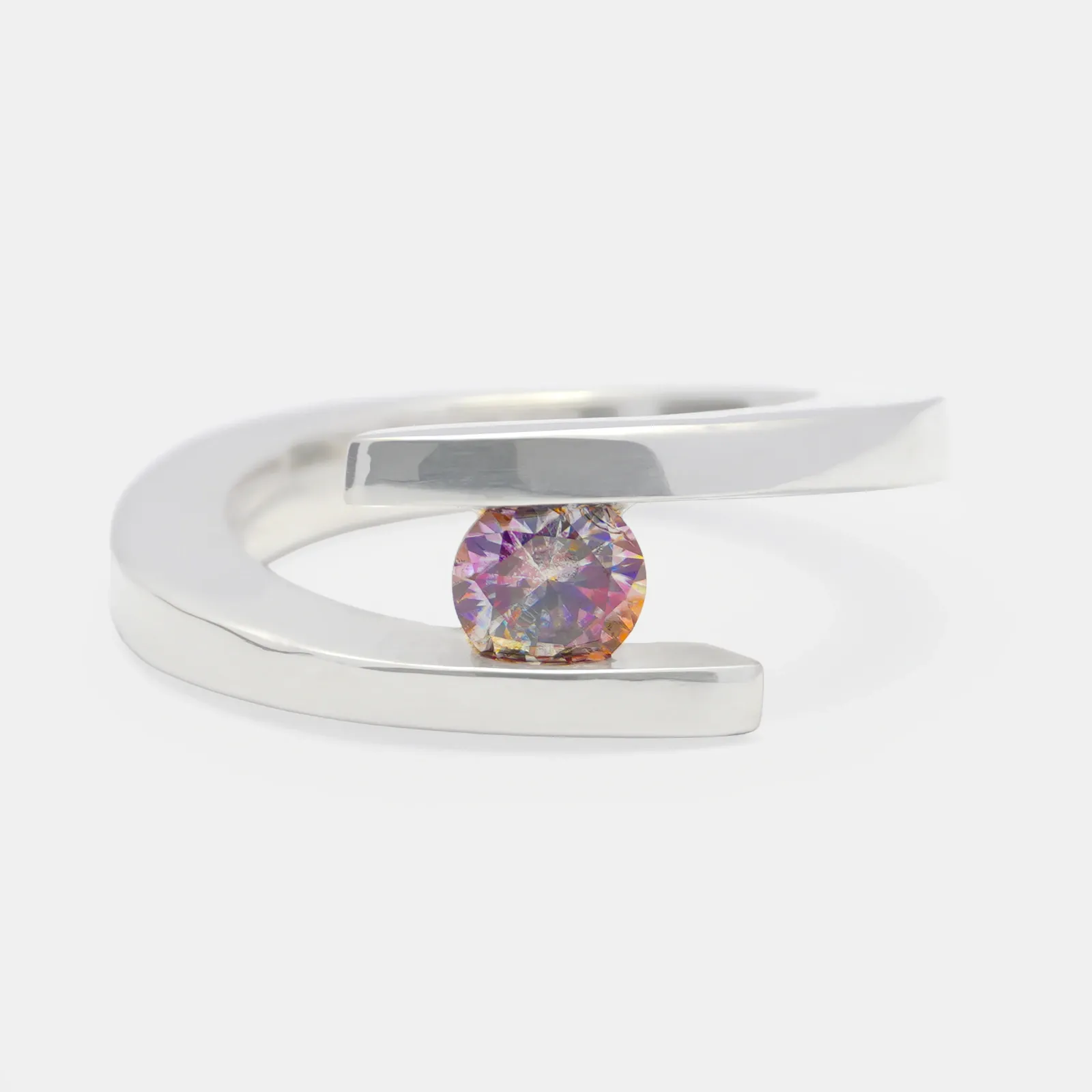 Anillo de plata de forma envolvente visto de frente, con una moissanita redonda de destellos rosados y violetas sostenida entre los dos extremos del aro.