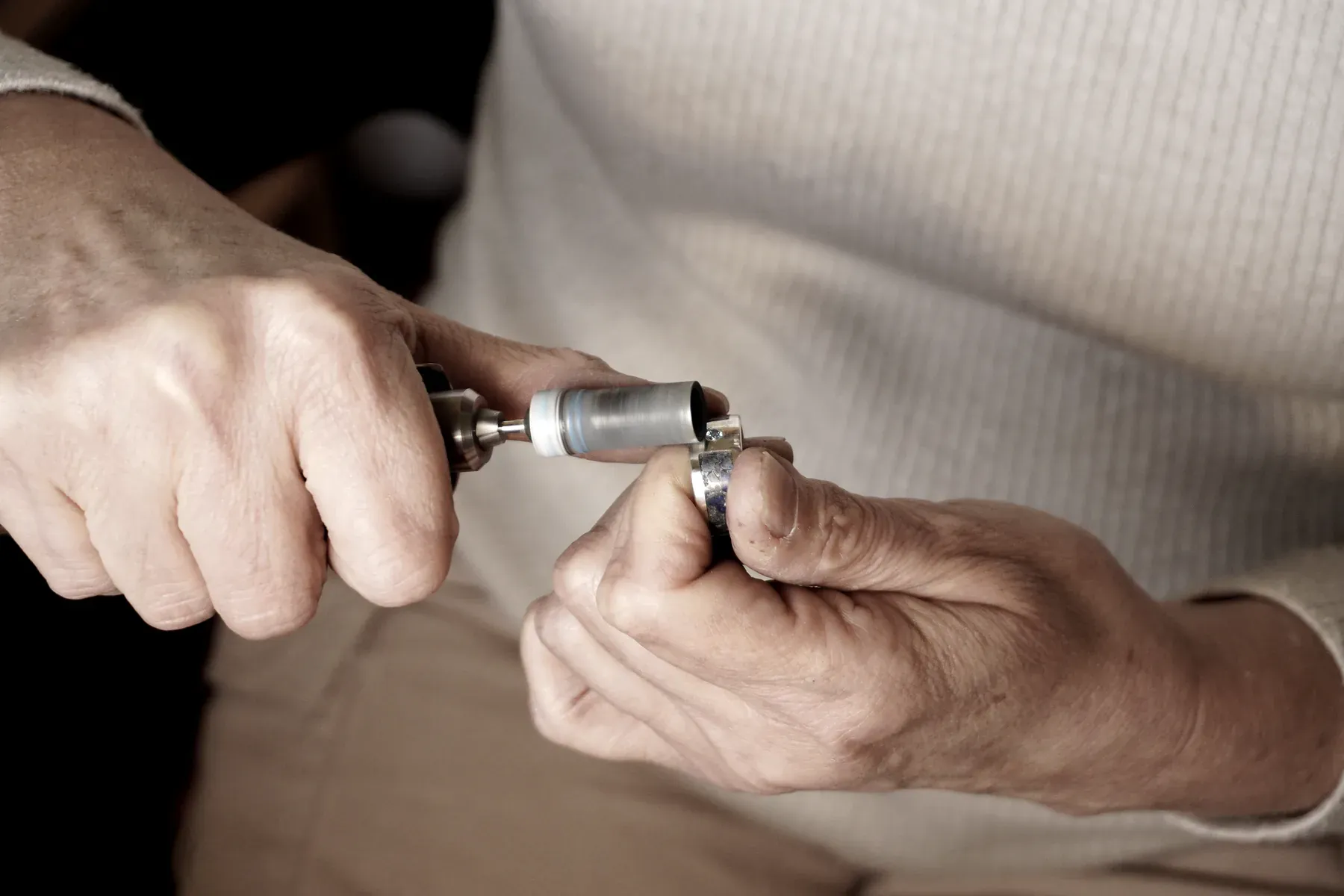 Dos manos sostienen un anillo mientras lo trabajan con un micromotor.